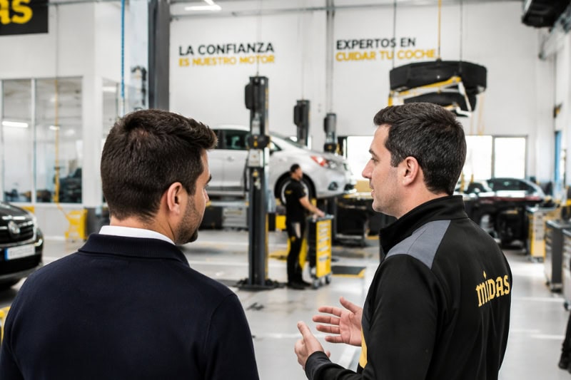 Un mecánico y franquiciador de Midas hablan dentro del taller mecánico.