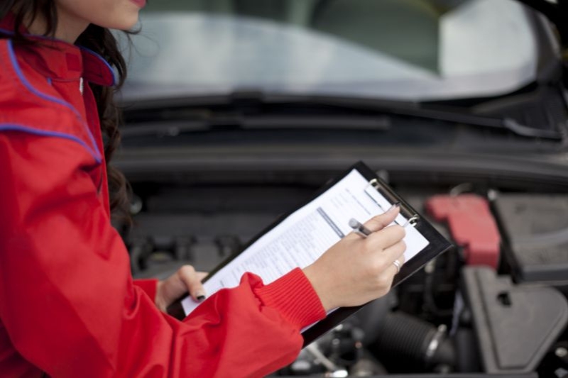 Una mecánica mujer hace un checklist de revisión de coche.