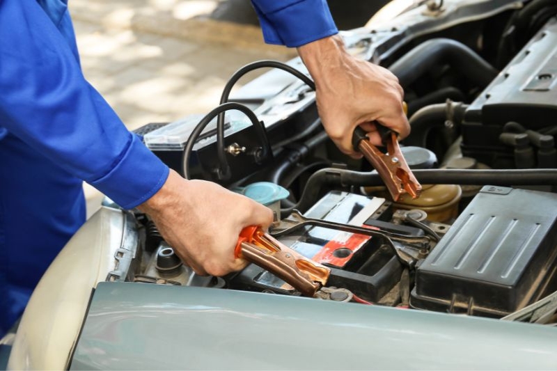 Un mecánico aplica pinzas sobre la batería de un coche.