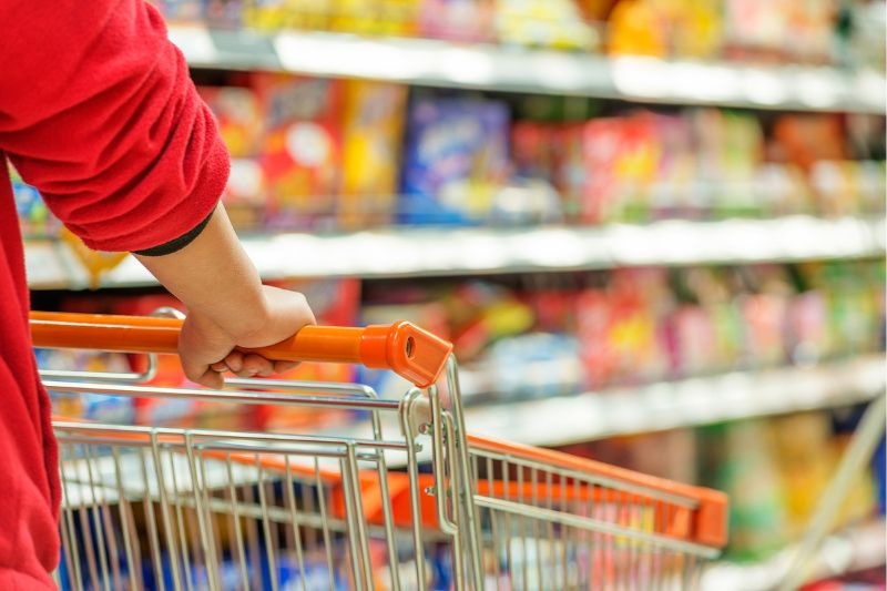 Una persona pasea un carrito de la compra por el pasillo de un supermercado.